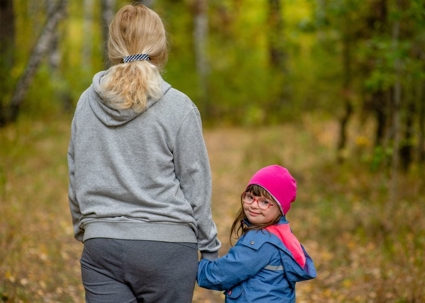 girl with down syndrome walks with her mother in autumn park