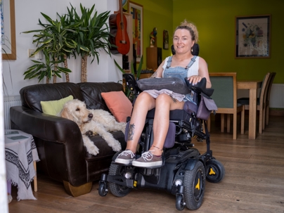 Woman who uses motorized wheelchair with her dog in living room