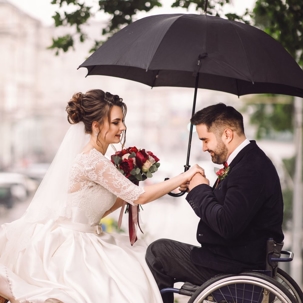 Bride and groom in the wheelchair kissing on the bench in the park shutterstock