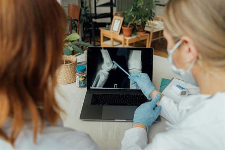 doctor and patient looking at x-ray of knee on laptop