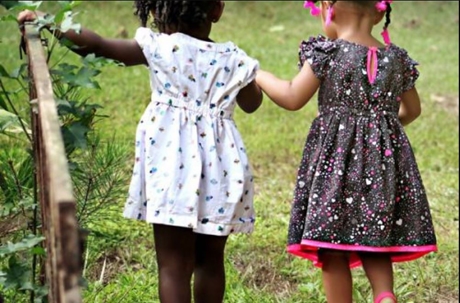 two little girls in dresses holding hands outside