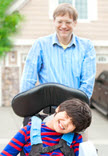 special needs child in wheel chair pushed by father